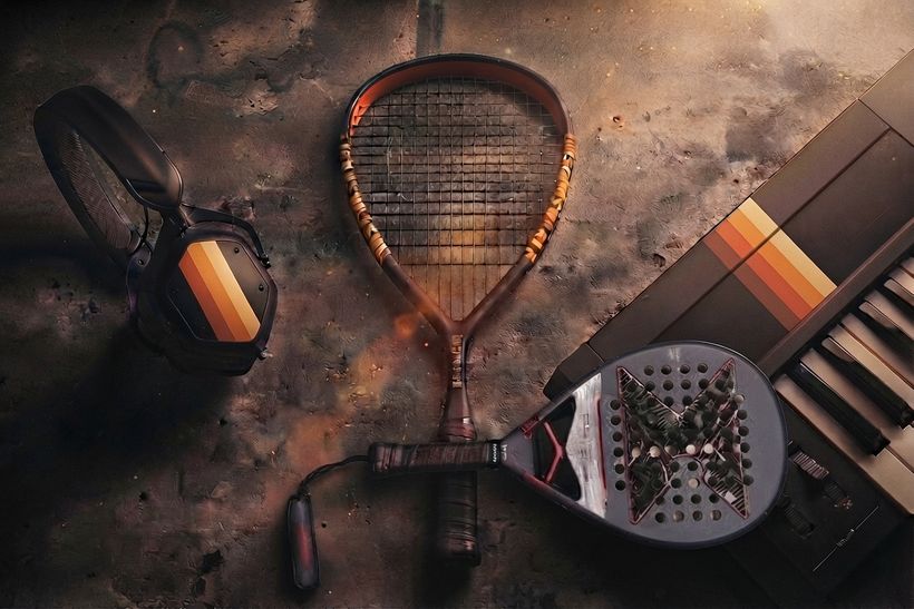 Casque audio, raquettes et clavier pos&eacute;s sur un sol textur&eacute;